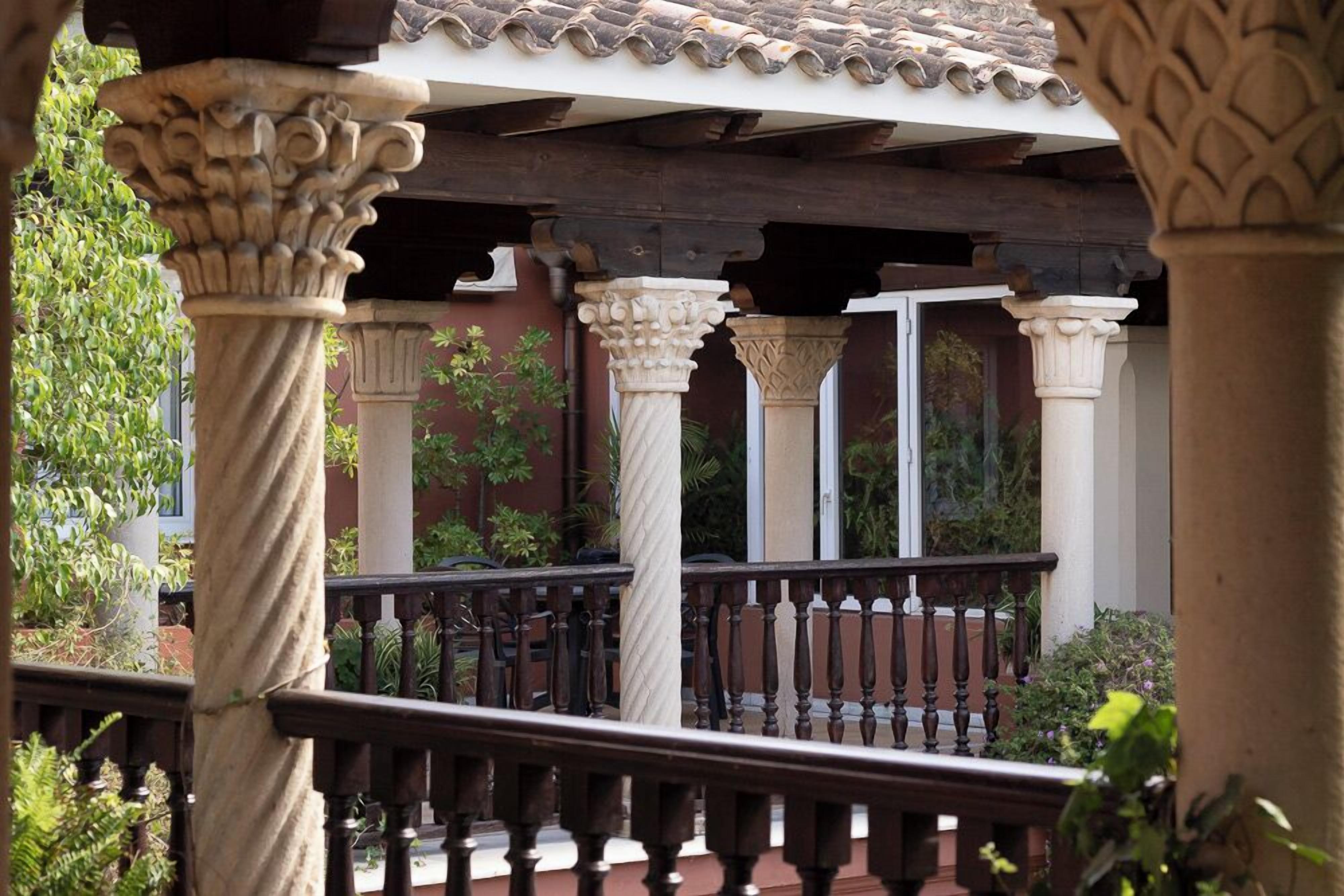 Un espacio al aire libre cubierto con columnas de piedra y barandilla de madera.