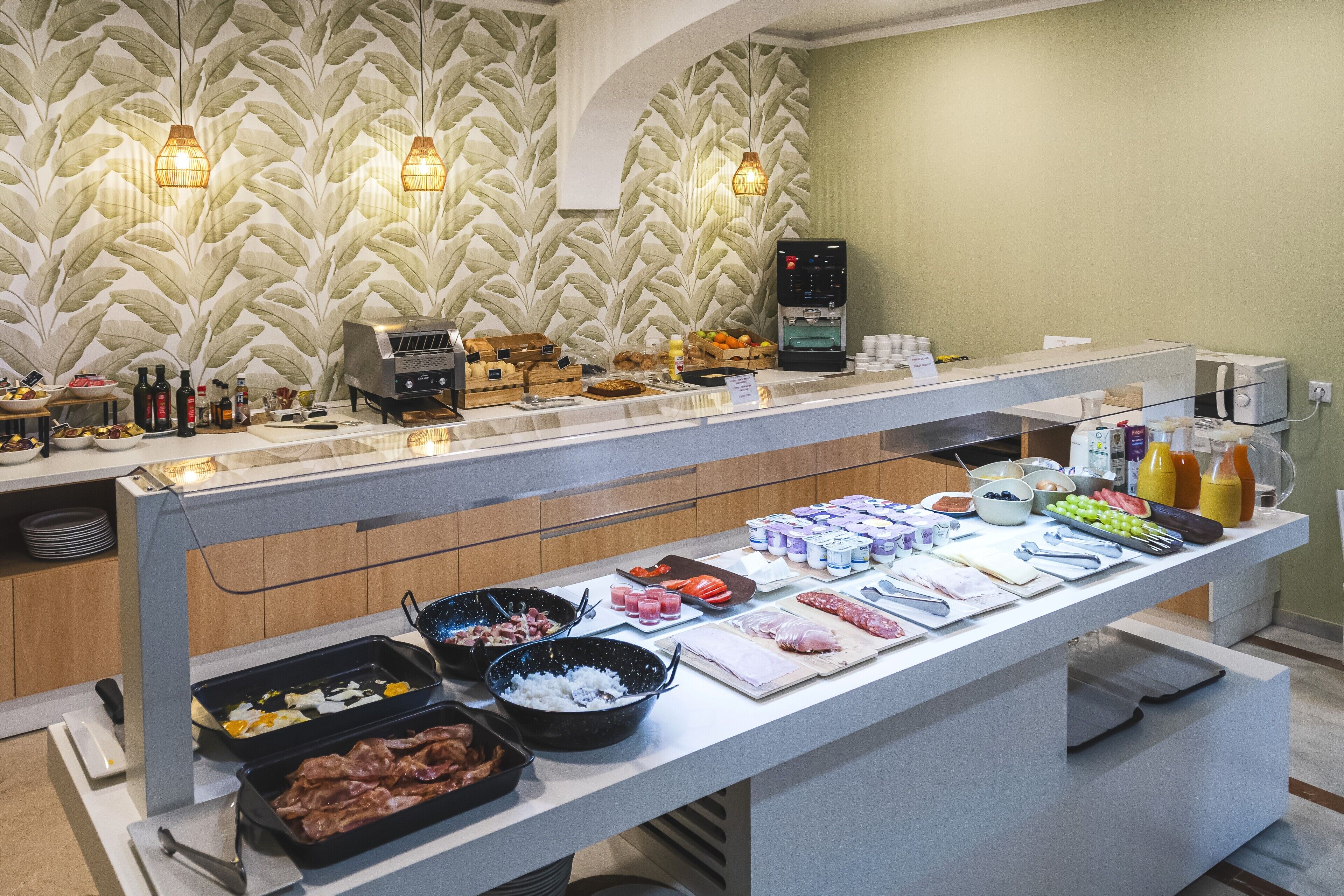 Un buffet proposant une variété de plats, un coin café et un mur décoratif orné d’un motif de feuilles.