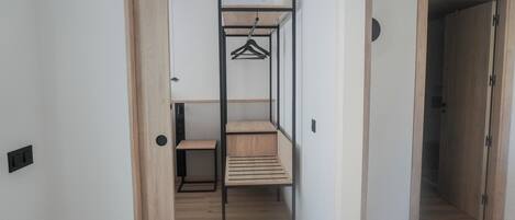 A hallway with a wooden floor, a metal-framed bunk bed, and a small wooden bench.
