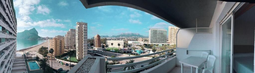 A balcony with a view of a beach, cityscape, and mountains.