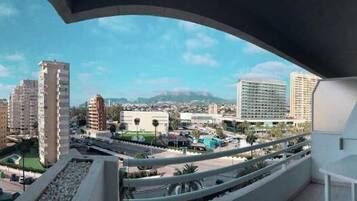 Un balcón con vistas a la playa, el paisaje urbano y las montañas.
