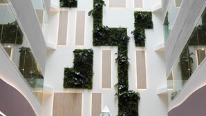 Un intérieur moderne doté d’un atrium central, de rampes en verre et d’un motif géométrique sur un mur.