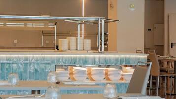Un restaurante moderno con una barra alargada, varias mesas y un salpicadero decorativo.