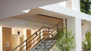 Un intérieur moderne avec un escalier, un canapé blanc et deux lampadaires.