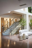 A modern interior with a staircase, a white sofa, and two floor lamps.