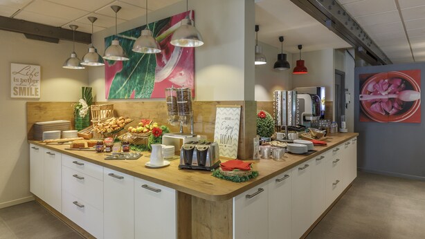 Un buffet pour le petit-déjeuner avec divers aliments, une machine à café et un panneau indiquant : « Profitez de la journée ».