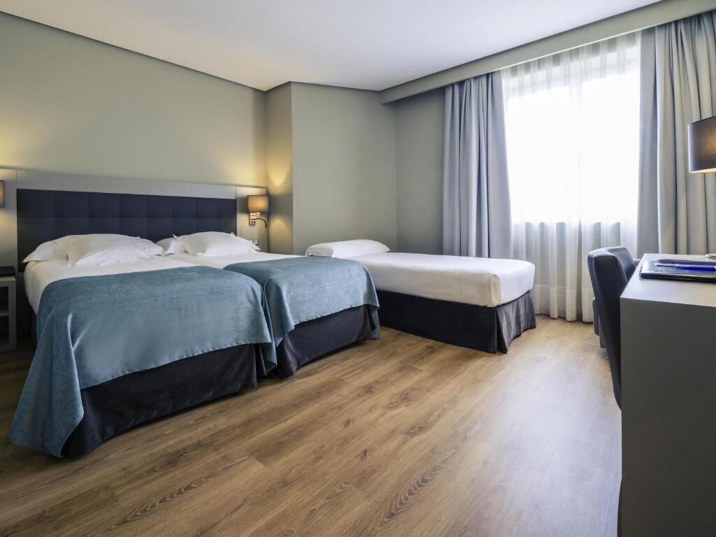 Een hotelkamer met twee bedden, een bureau en een stoel.