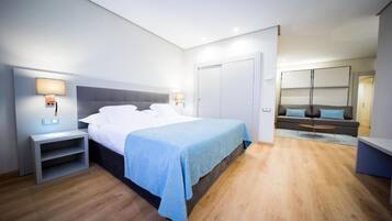 Una habitación de hotel moderna con una cama grande, mesitas de noche, un sofá y un armario.