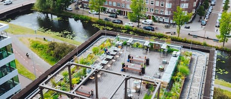 Une terrasse sur le toit avec des sièges en plein air, une rivière et des bâtiments environnants.
