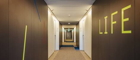 A hallway with a carpeted floor, a blue carpet runner, and walls with the word "LIFE" illuminated in yellow.