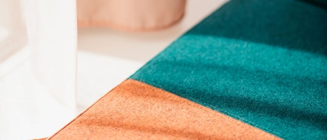 Primer plano de una cama con una colcha a rayas naranja y verde azulado.