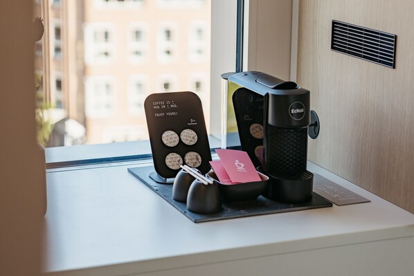 A coffee machine and a card holder with coffee cups on a table near a window. - Hotel Casa Amsterdam (Amsterdam)