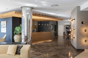 A modern lobby with a reception desk, seating area, and decorative wall art.