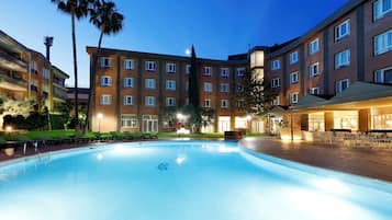 Una piscina al aire libre de temporada, sombrillas