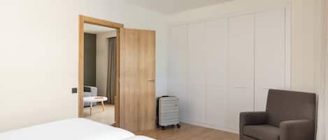 Una habitación de hotel con cama, una silla, un armario y una maleta.