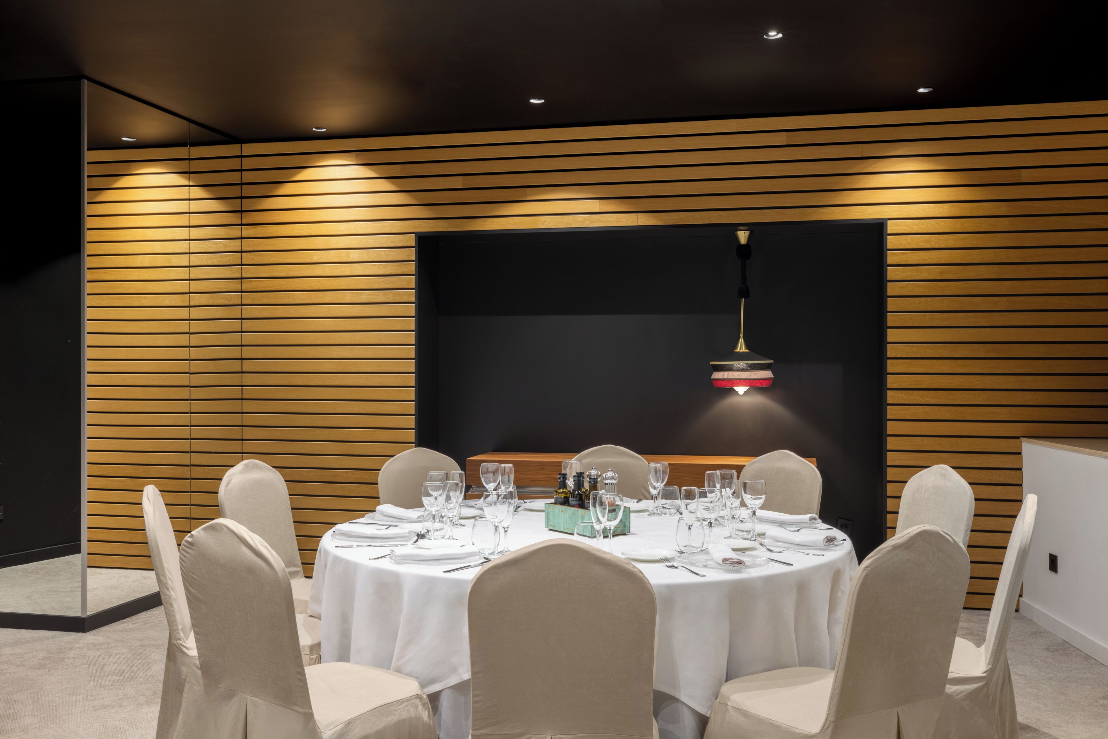 Un salón de conferencias con mesas redondas, manteles blancos y sillas color beige.