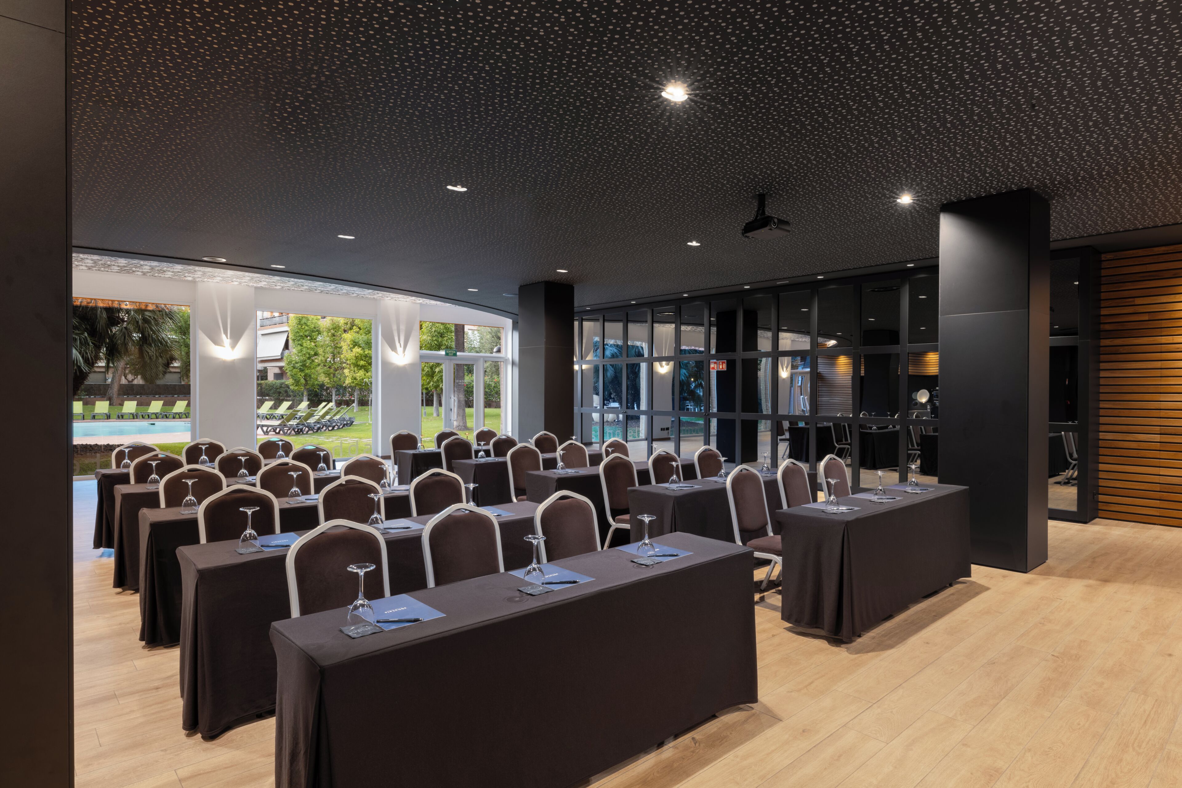 A conference room with tables and chairs, large windows, and a ceiling with a starry pattern.