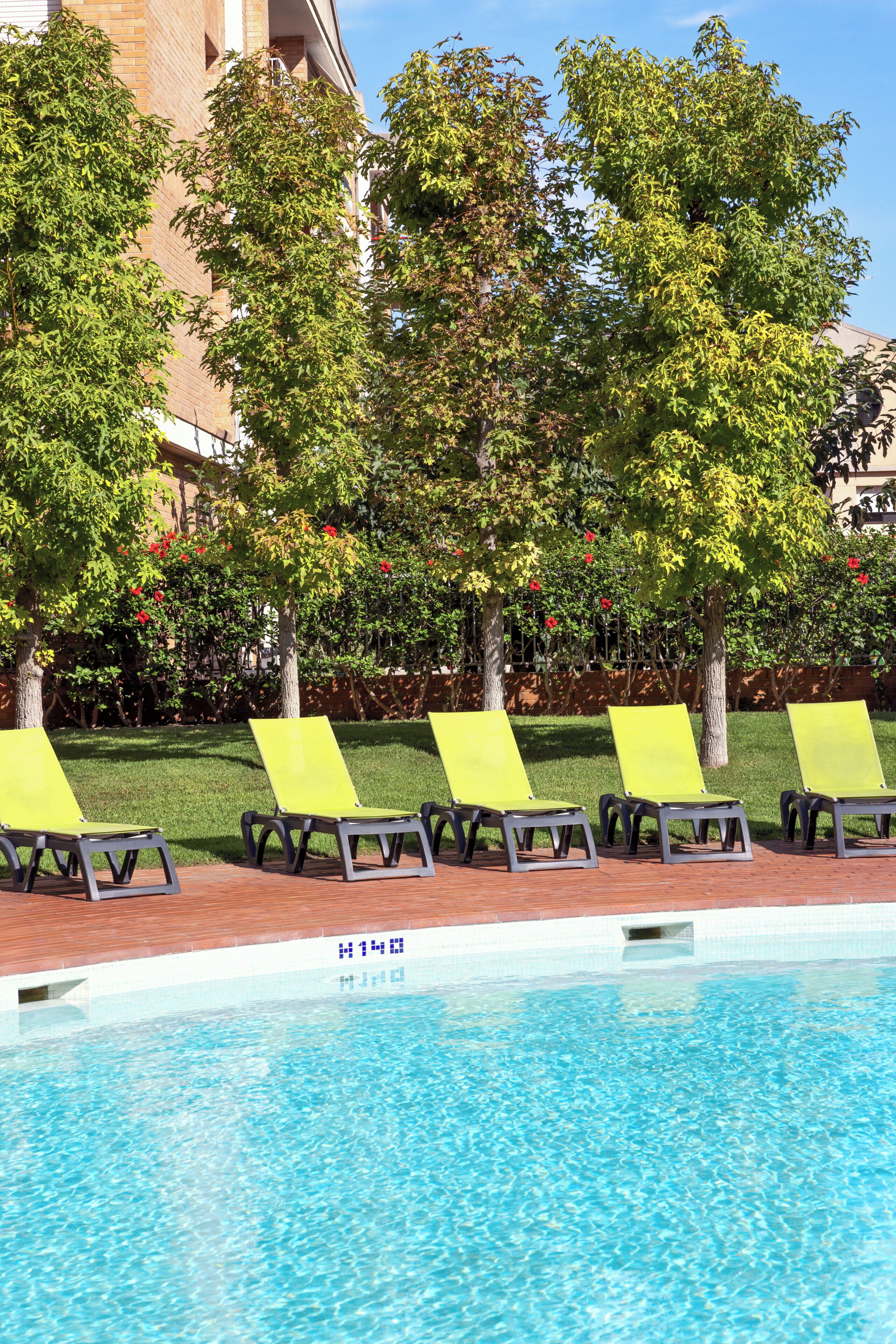 A poolside area with lounge chairs and a brick pool.