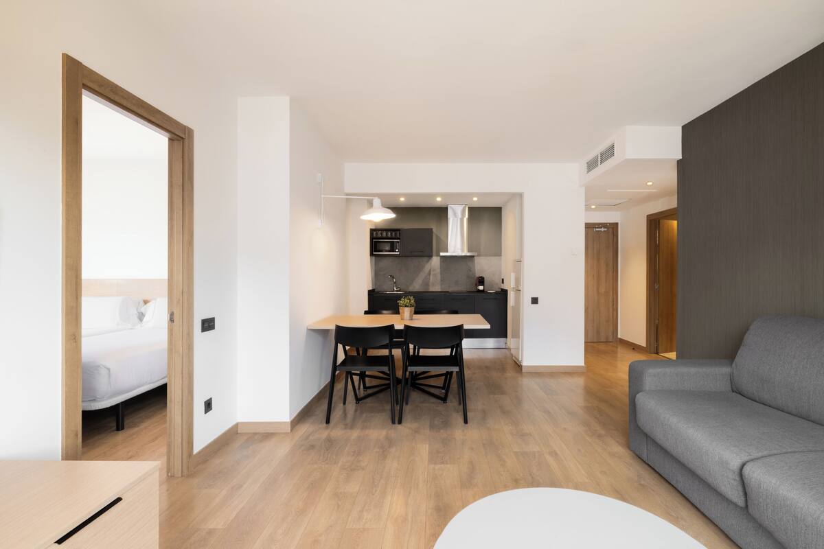 Un apartamento moderno con comedor, cocina y un sofá gris.