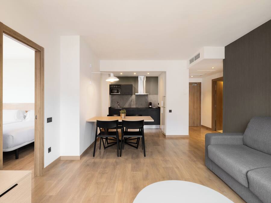 Eine moderne Wohnung mit Essbereich, Küche und einem grauen Sofa.