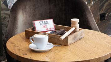 Una mesa redonda de madera con una taza y platillo blancos, una bandeja de madera con una caja etiquetada 'CREO' y un rodillo de amasar de madera.