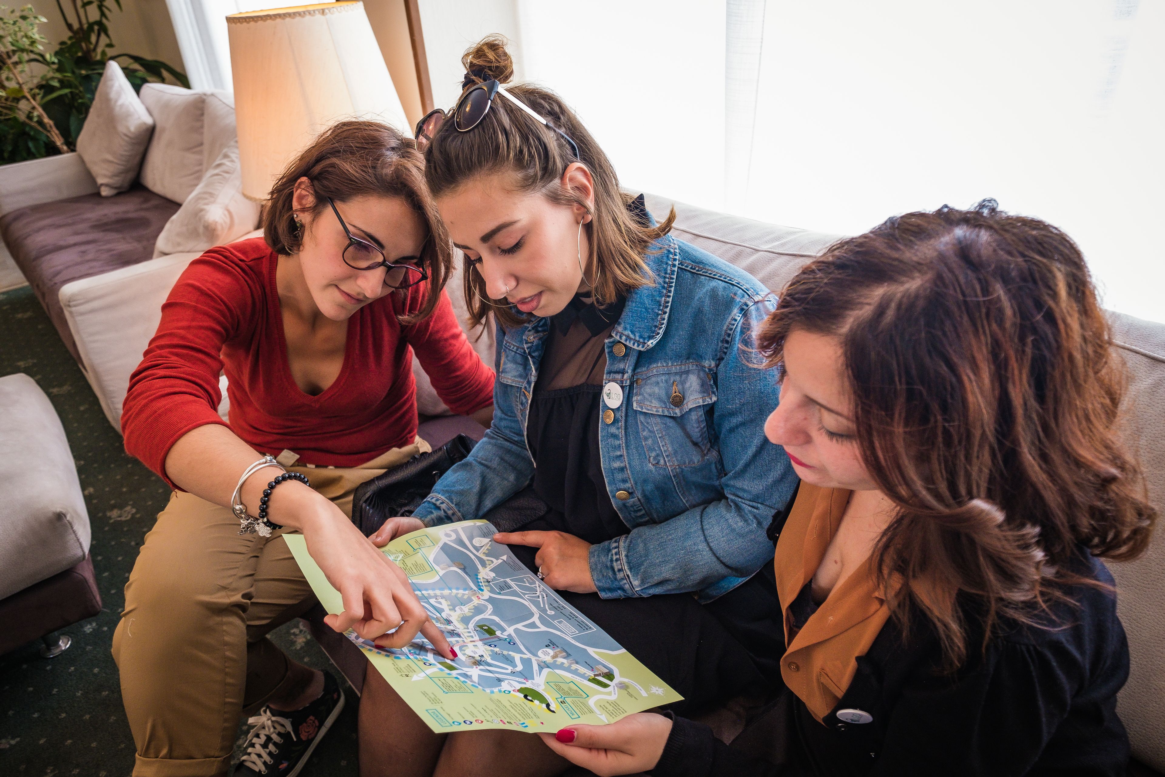 Three people sitting on a couch, looking at a map.