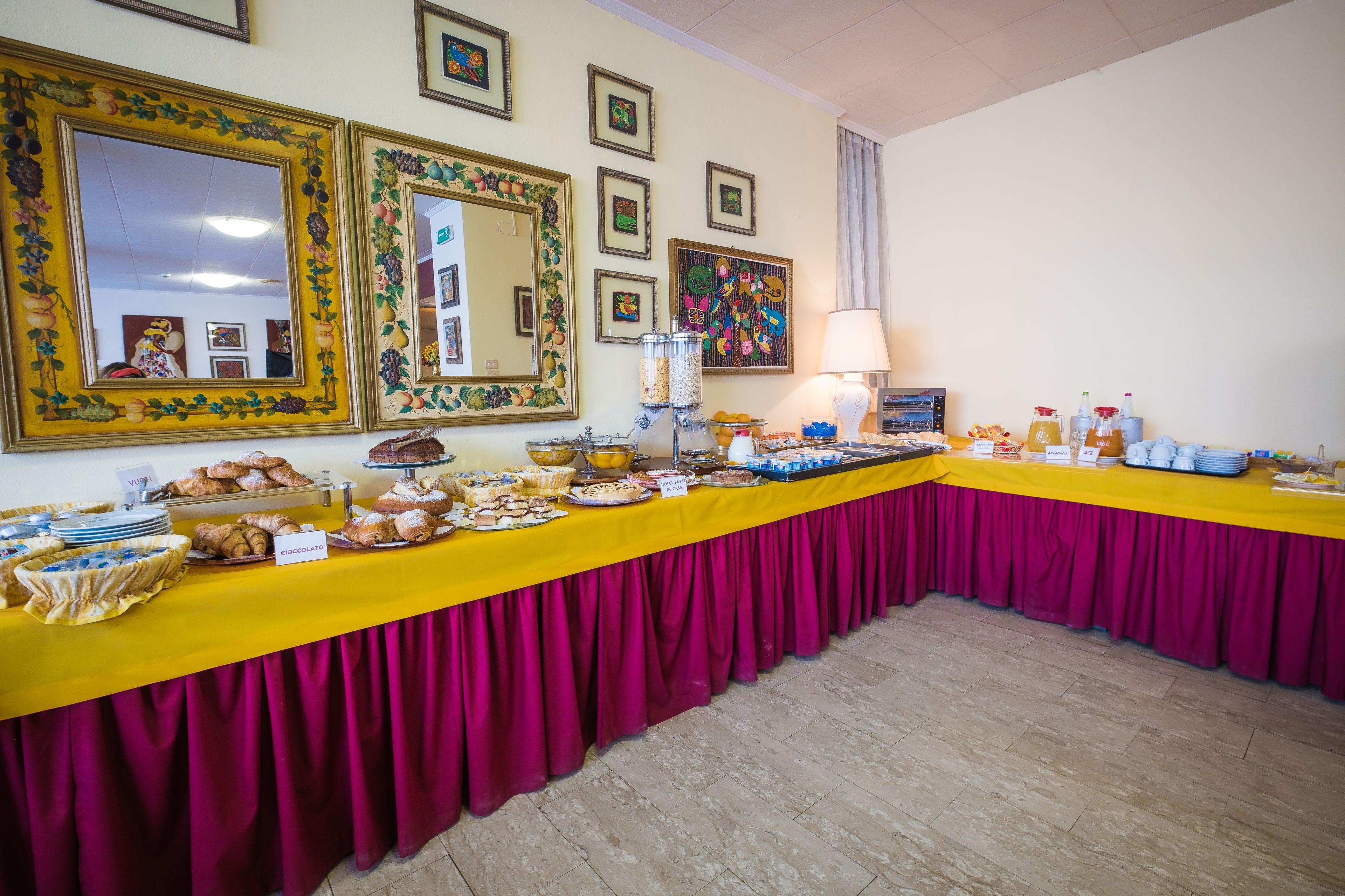 A buffet table with various food items and a yellow tablecloth.