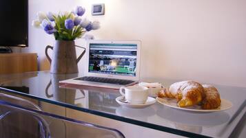 Ein Laptop steht auf einem Glastisch zusammen mit einer Tasse und zwei Croissants.