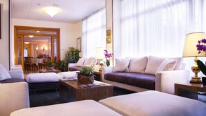 A hotel lobby with a seating area, a dining area, and a reception desk. - Hotel Ilgo (Perugia)