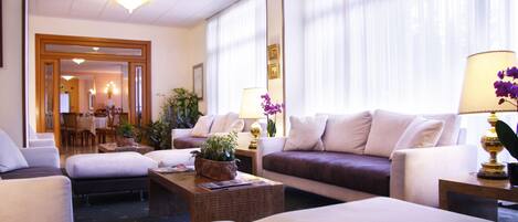 Un vestíbulo de hotel con una zona de estar, un comedor y una recepción.