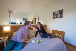 A hotel room with a bed, a bedside table with a cup and plate, and a mirror on the wall. - Hotel Ilgo (Perugia)