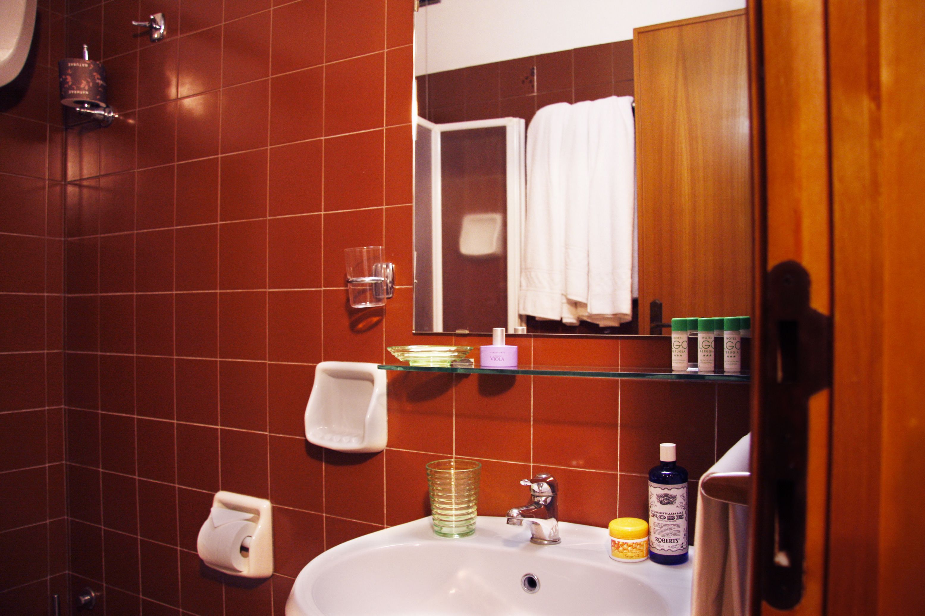 Un baño con un lavabo blanco, dispensador de jabón de vidrio y un espejo con marco de madera.