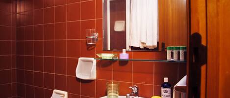 A bathroom with a white sink, glass soap dispenser, and a mirror with a wooden frame.