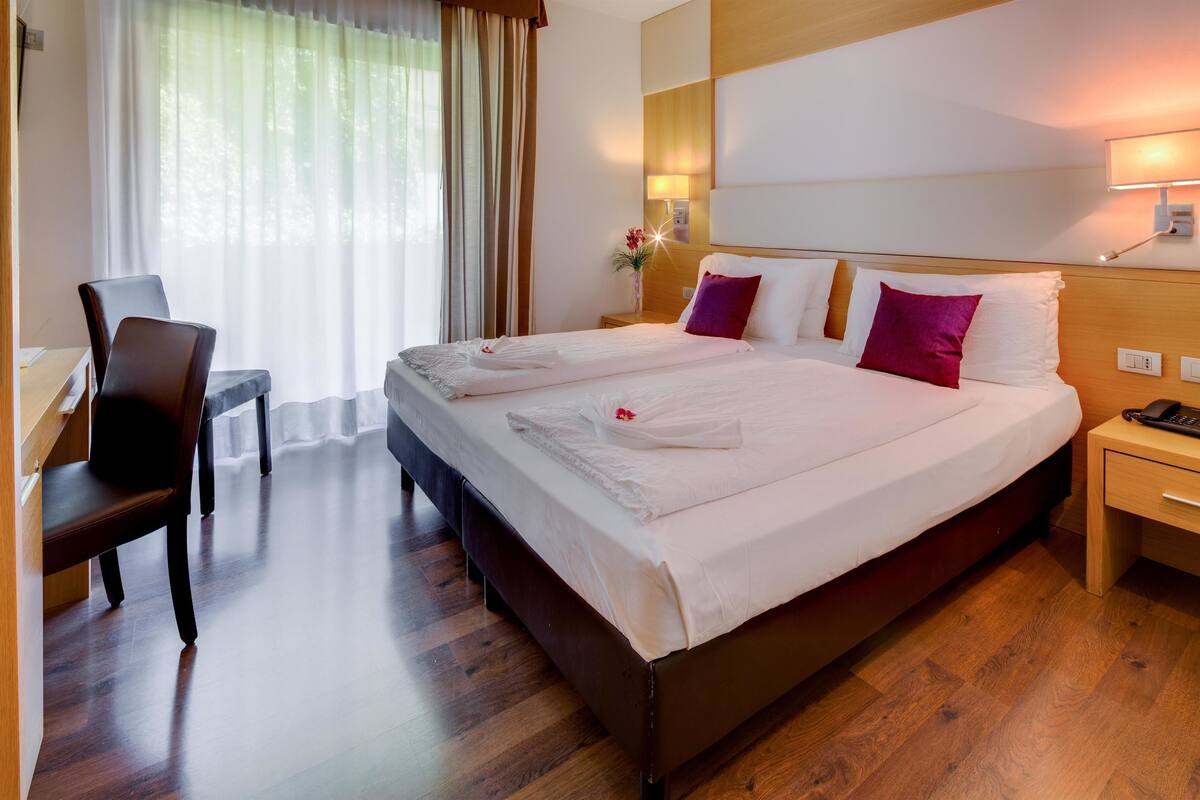 A hotel room with a large bed, a desk, and a chair.