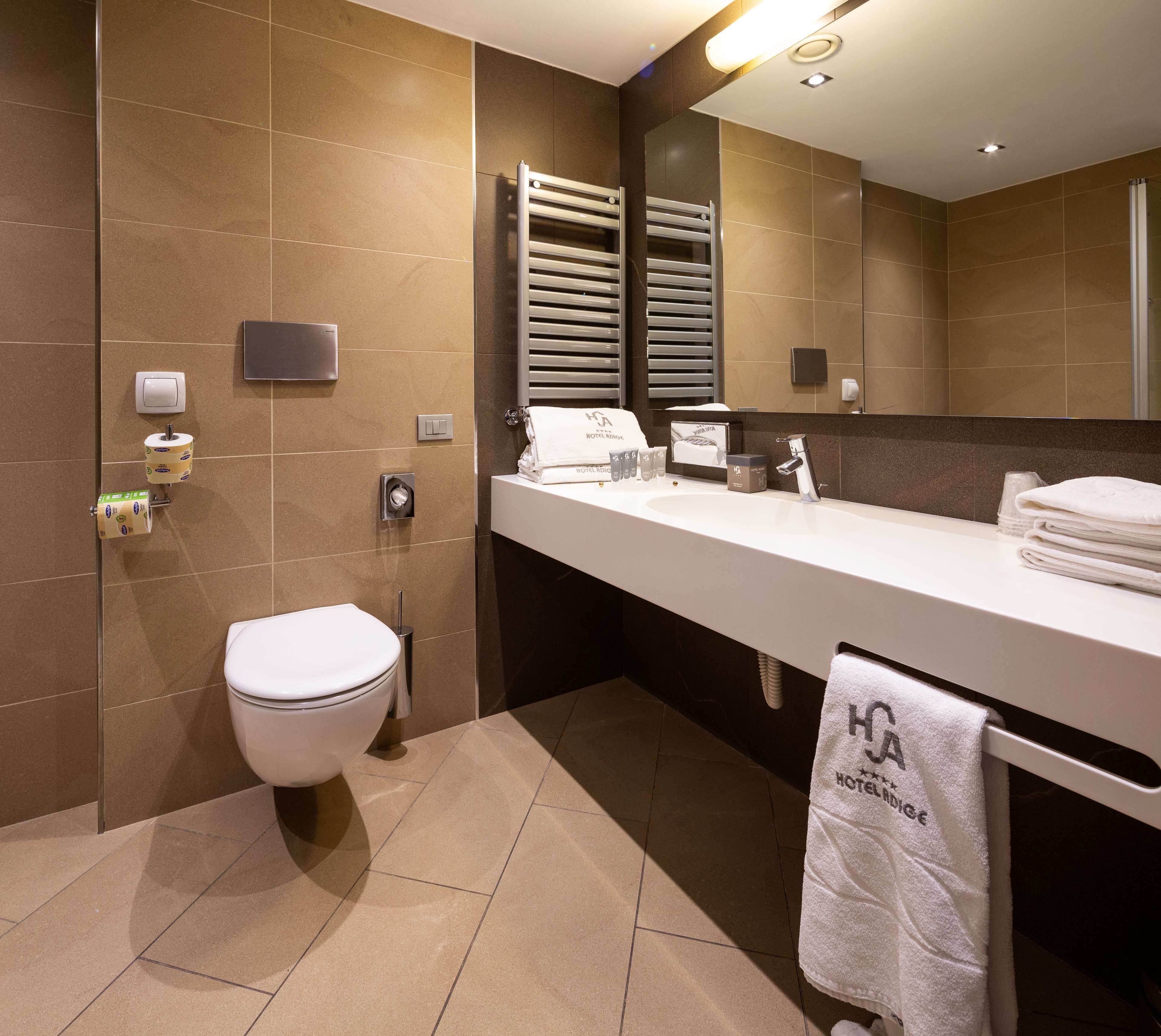 A modern bathroom with a toilet, sink, towel rack, and a mirror.