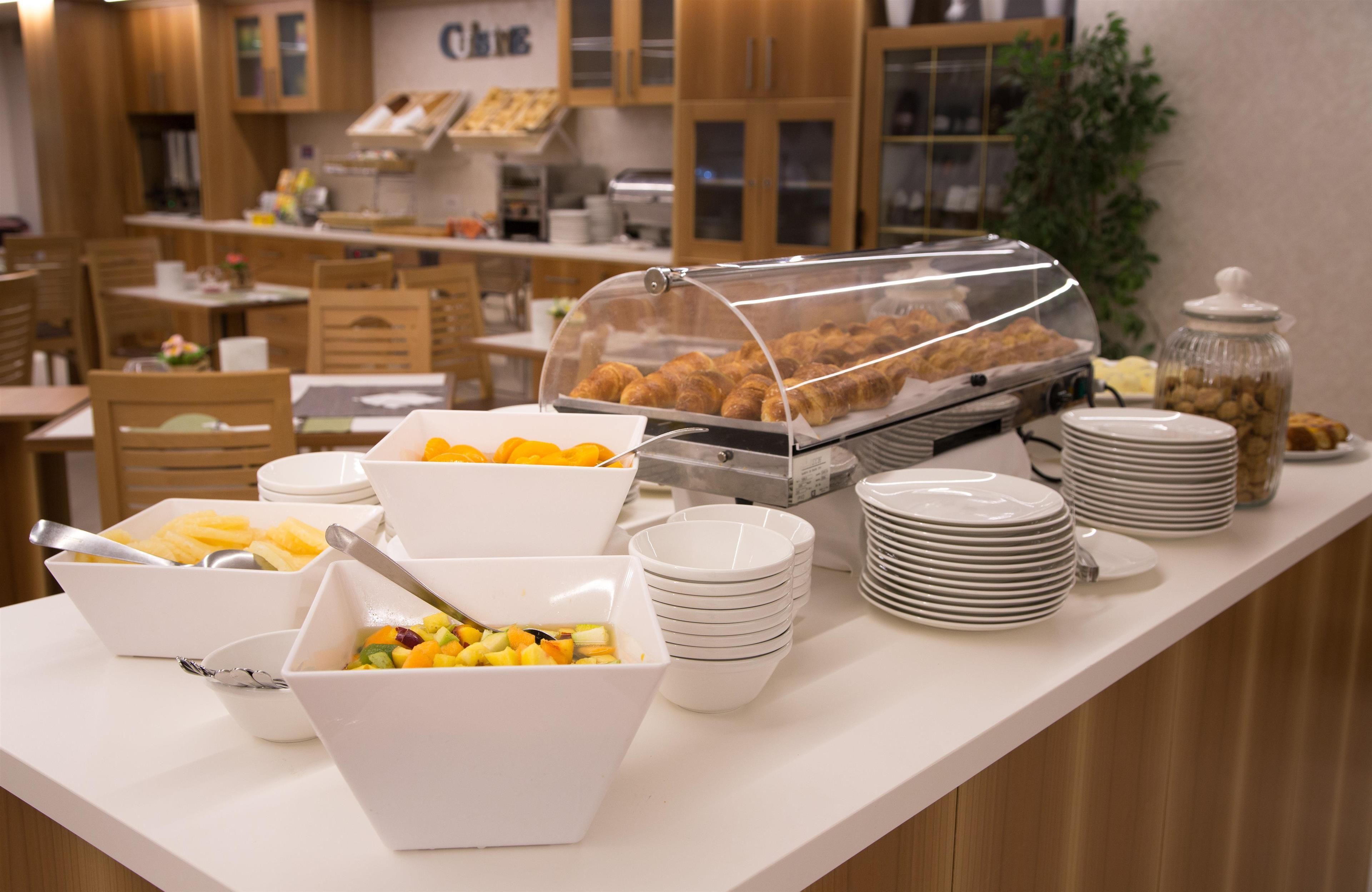Montaje de bufé con diversos alimentos, incluyendo frutas y pasteles, además de una estación de café.