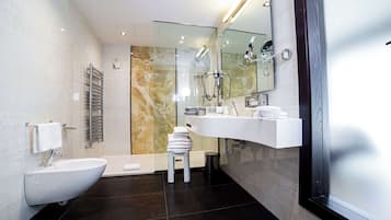 Ein modernes Badezimmer mit integriertem Bidet, einem Waschtisch mit Spiegel und einer Duschkabine aus Glas.