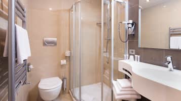A modern bathroom with a glass-enclosed shower, a toilet, a sink with a vanity, and a bathtub.