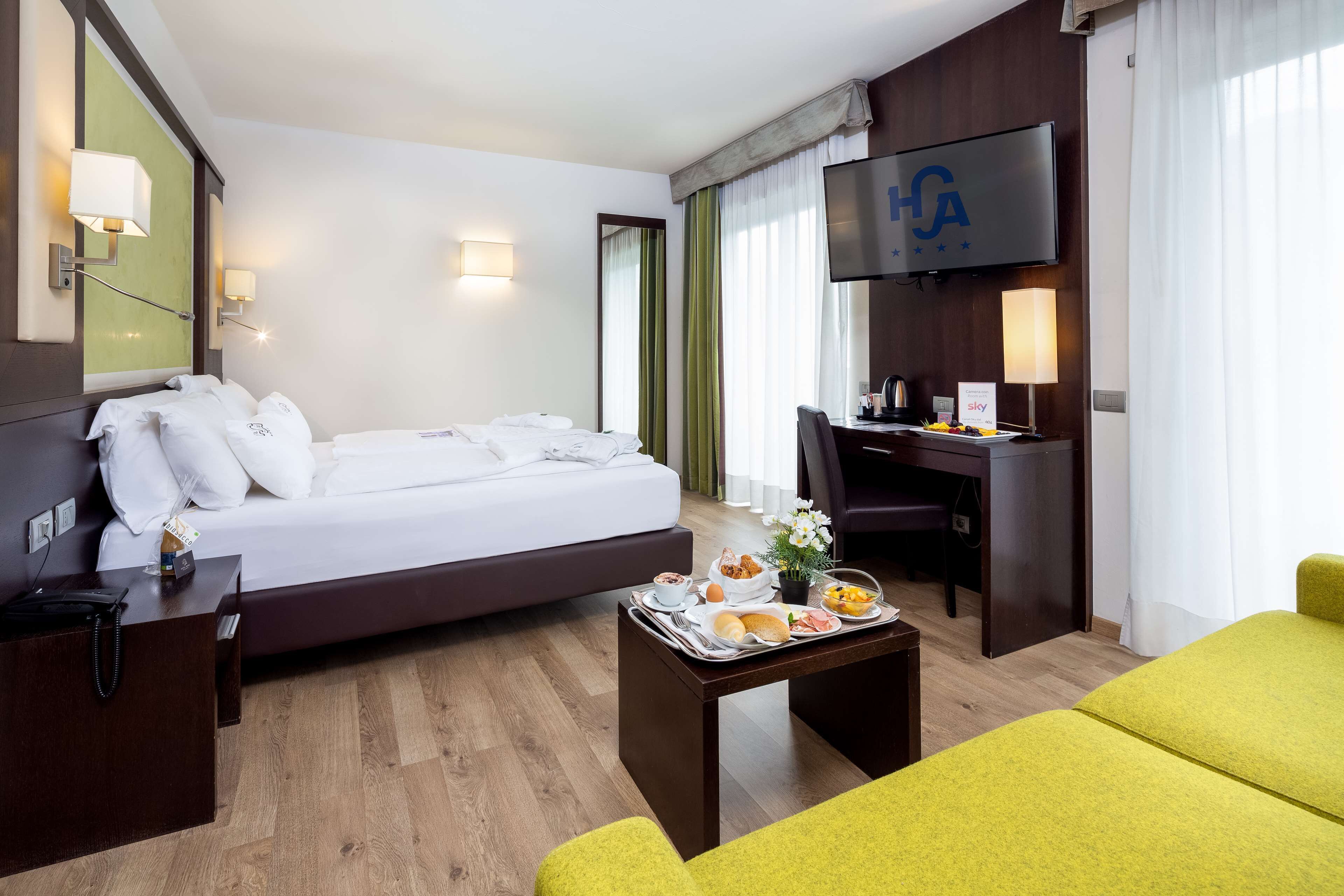 Ein Hotelzimmer mit Bett, Schreibtisch, Fernseher und Frühstückswagen.