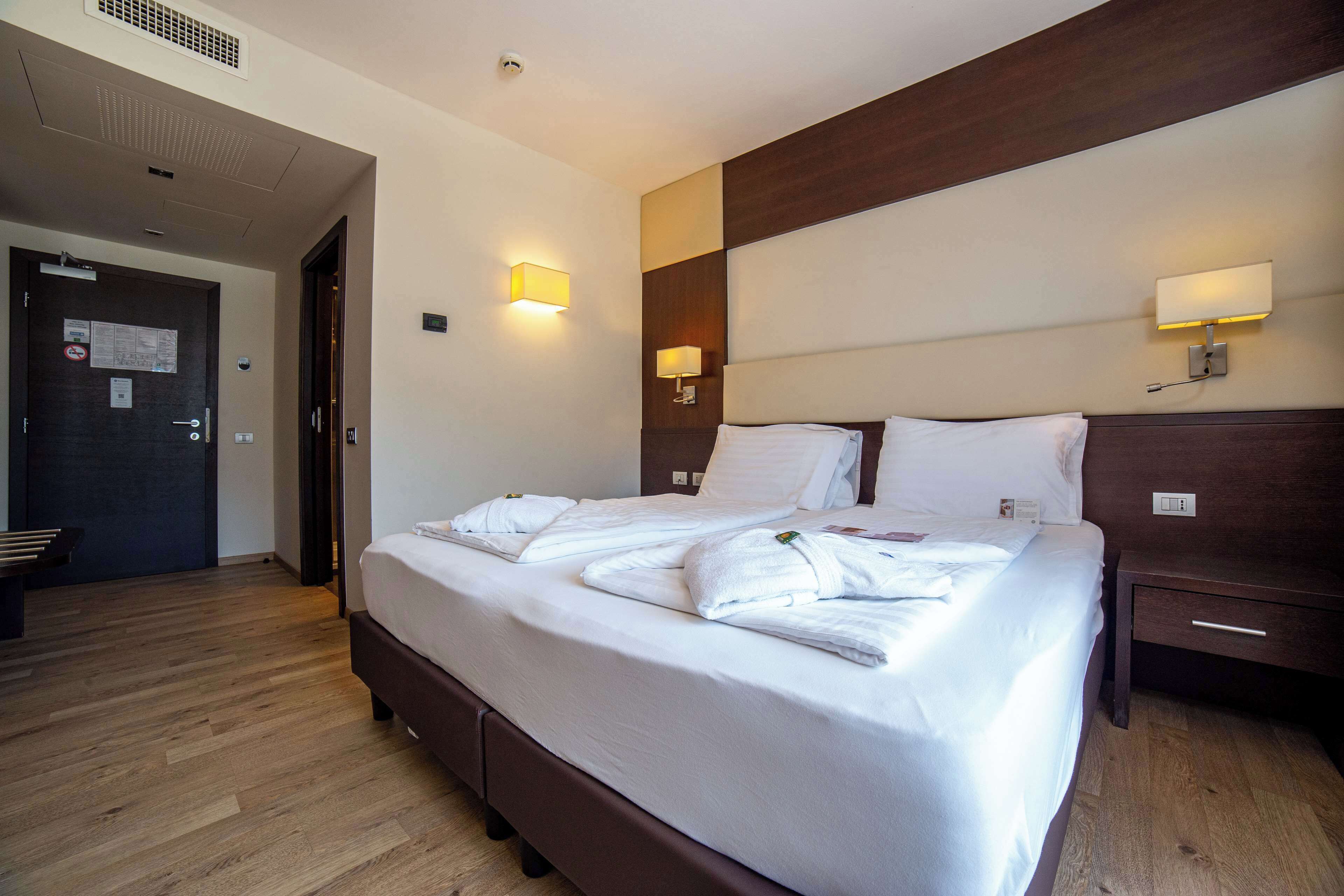 Ein Hotelzimmer mit einem großen Bett, Nachttischen und Wandlampen.