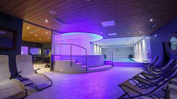 Ein Wellnessbereich mit Pool, Sitzgelegenheiten und einer Rezeption.