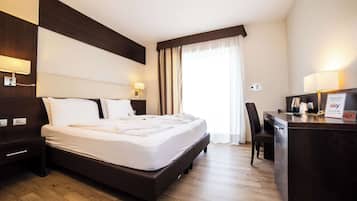 Una camera d'albergo con un letto grande, una scrivania con un computer e una finestra con tende.