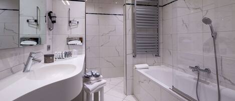 A modern bathroom with a large sink, mirror, towel rack, and a glass-enclosed shower area.