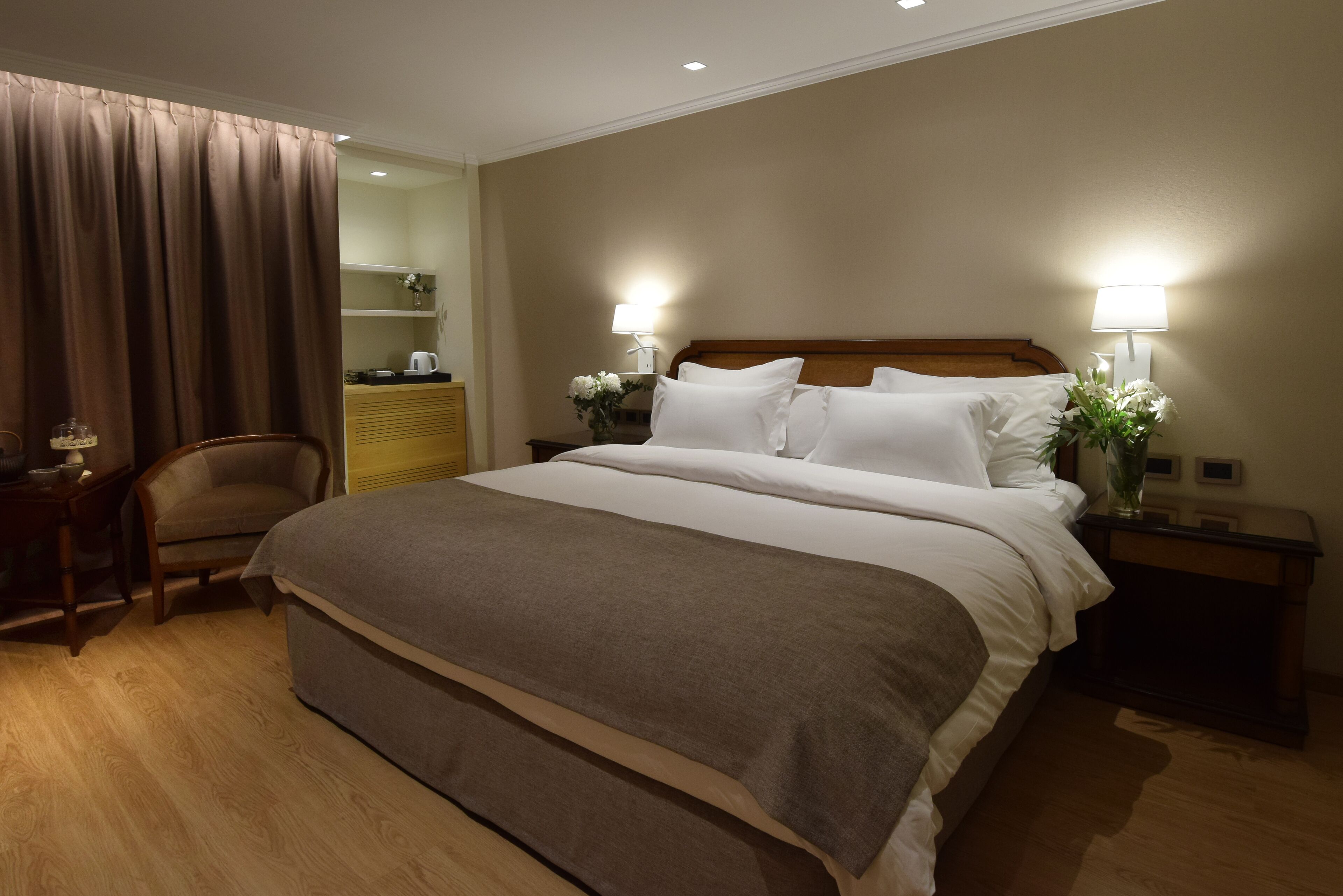Una habitación de hotel con una cama grande, dos mesitas de noche con lámparas, una silla, un escritorio y un armario.