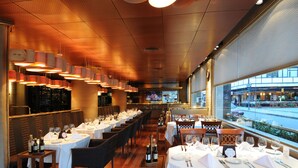 A restaurant with multiple tables set for dining, a bar area, and a view of the street outside. - Windsor Hotel And Tower (Córdoba)