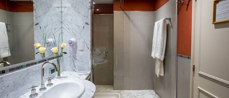 A bathroom with a marble sink, a glass-enclosed shower, and a towel rack.