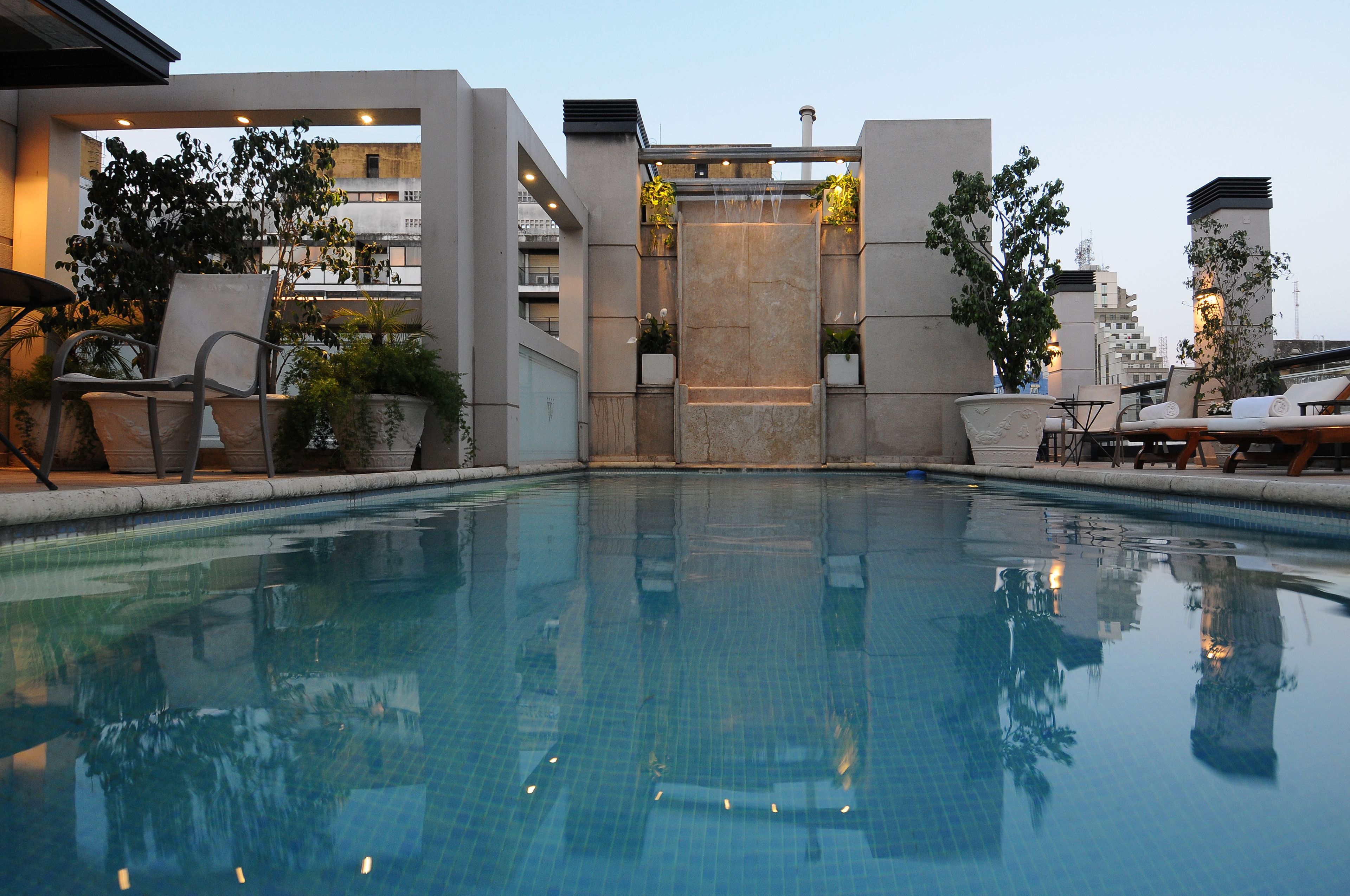 A swimming pool with a modern architectural design, surrounded by lounge chairs and potted plants.