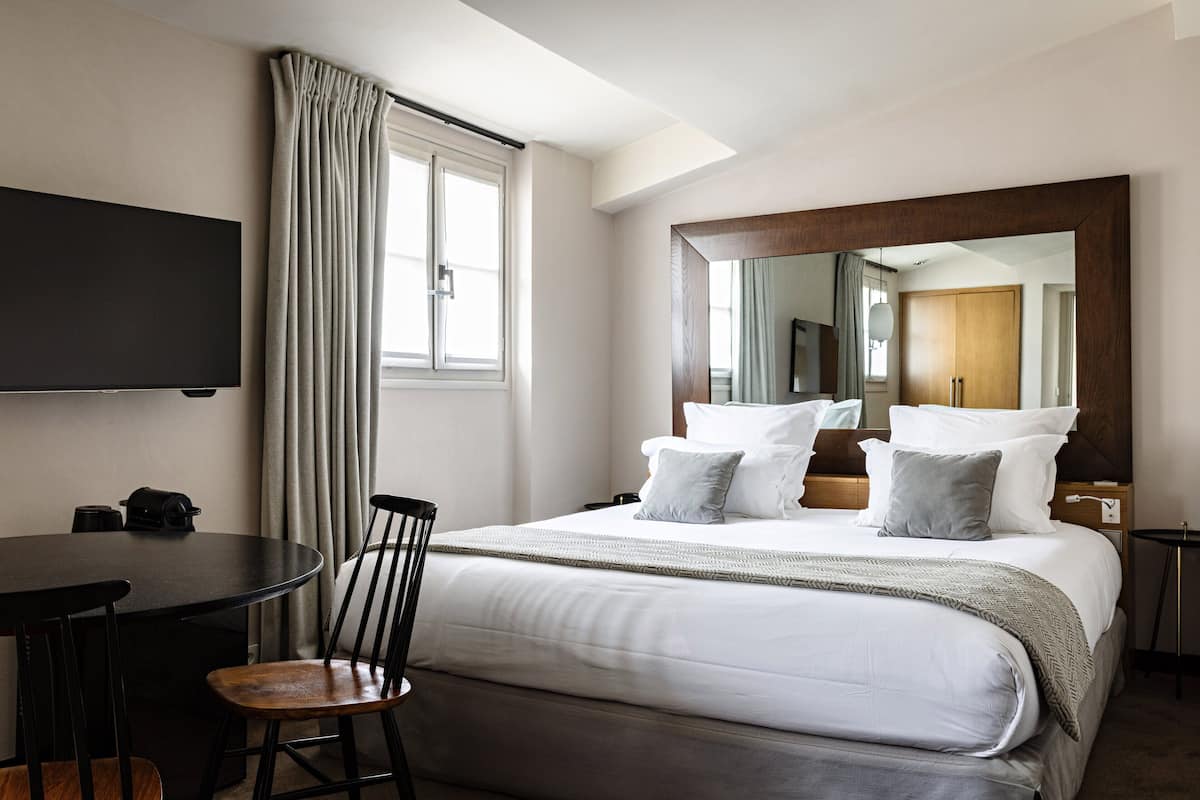 Une chambre d’hôtel avec un lit, une télévision, une table et une chaise.