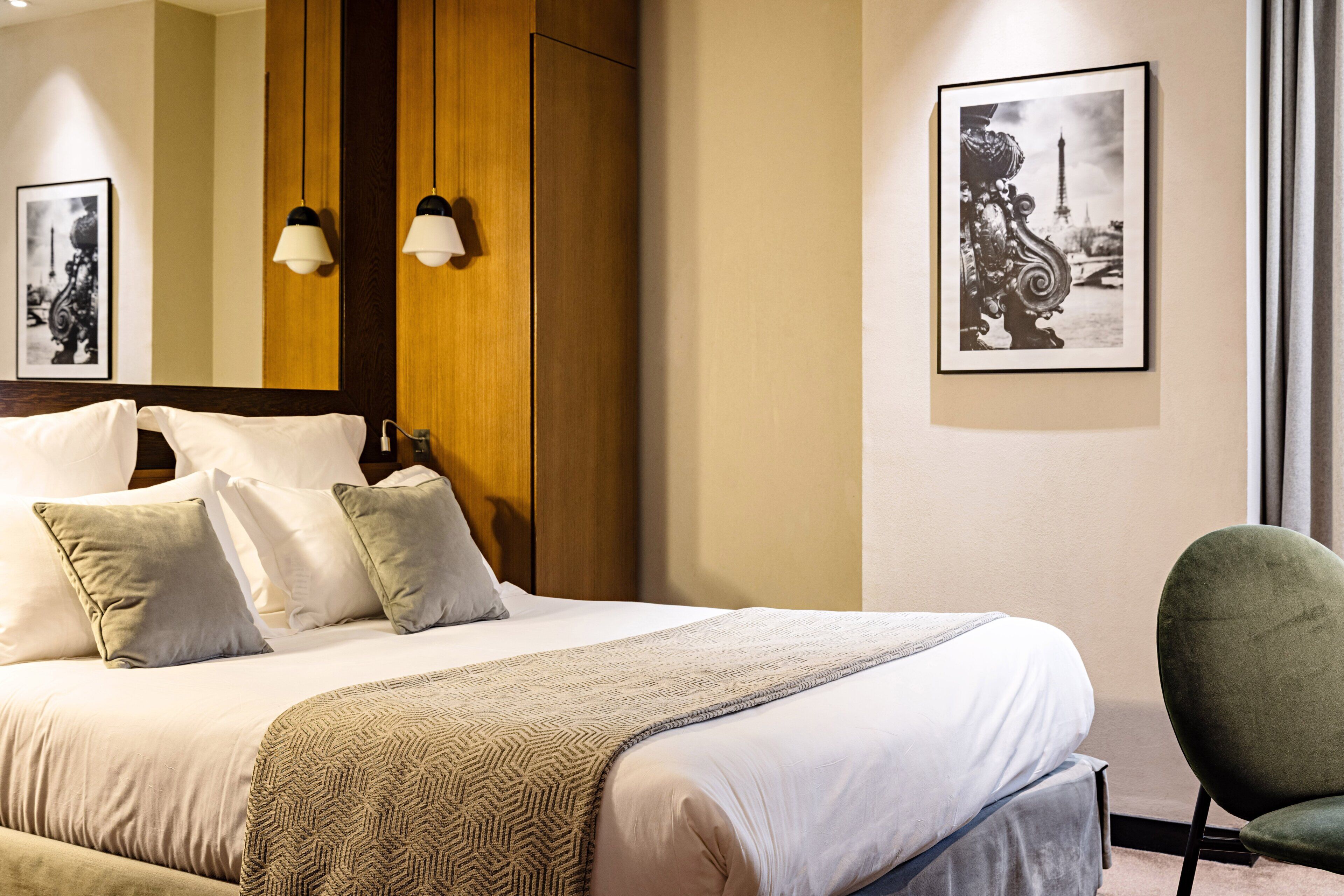 A neatly made bed with a patterned throw, a wooden headboard, and two wall-mounted lamps.