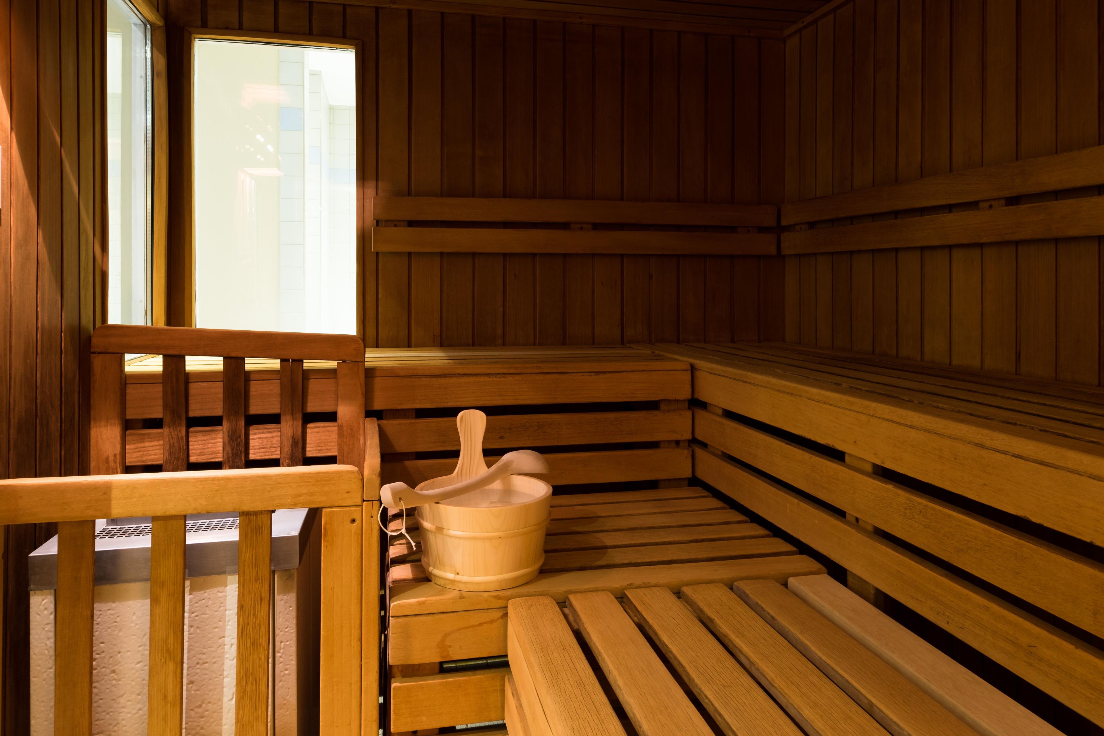 A sauna with wooden benches and a wooden bucket.